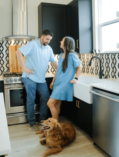 Couple posing with their dog in their kitchen