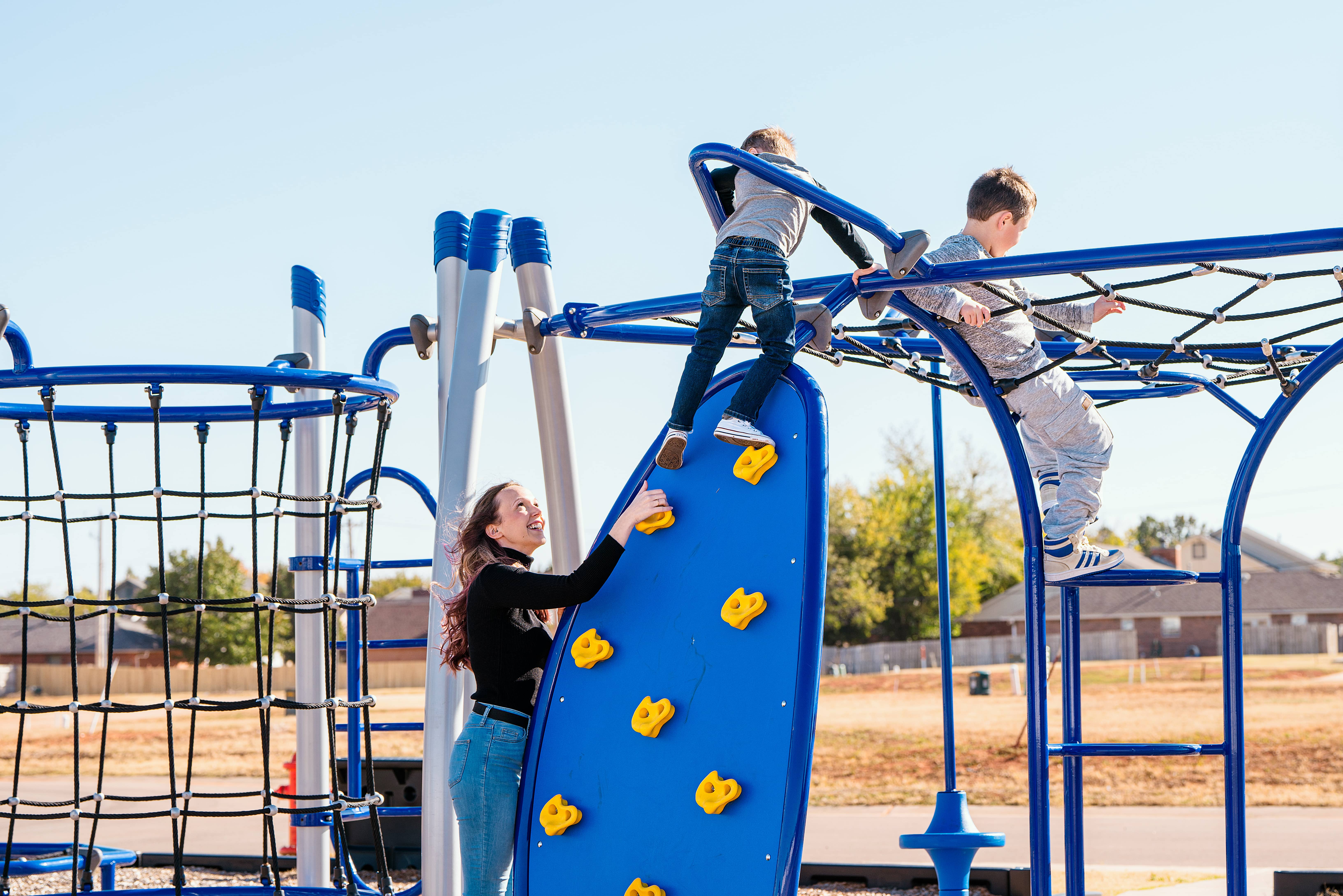 Mother and her two children playing on playground equipment in a TimberCraft community