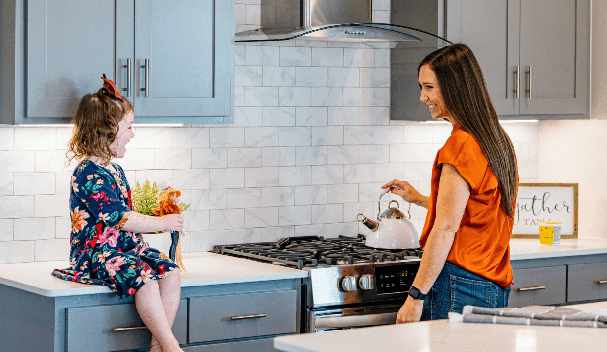 Mother and young daughter in their kitchen smiling